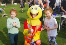 Runners celebrate as Run the Maine returns Twins Molly and Annie enjoy a photo op with Run The Maine mascot 'The Bird'. Photo: Max Lesser.
