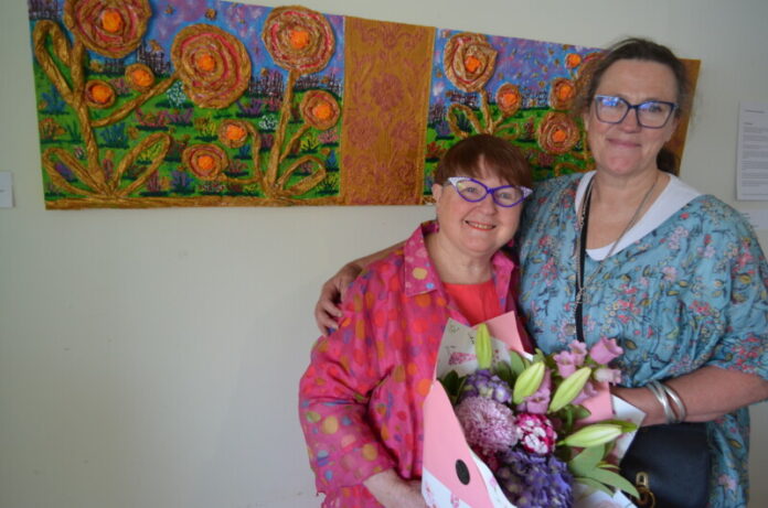 Castlemaine artist Heather Murrowood is pictured with one of her mentors and support workers Sarah Wallace-Smith and one of her vibrant works.