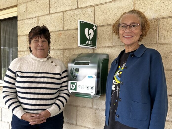 Sue Buckman from Defib for Life and Tonye Segbedzi from Neates Road Neighbourhood News, standing next to the new AED at Campbells Creek Community Centre.