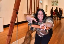 BIYAL brings connection and healing A new exhibition at Castlemaine Art Museum honours the Guildford Biyal (Red Gum) with works created from the large limb that fell in 2024 - a pivotal event for Dja Dja Wurrung people and the broader community. Narungga artist Sarah Jane Hall is pictured with her work Seven Sisters - Mangga Mangiardi. Photo: Jade Jungwirth.